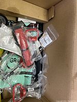 Top view of box with assorted hand tools and parts including red-handled items and packaged components