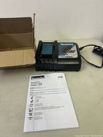 Makita DC18RC charger on table with user manual and open cardboard box.