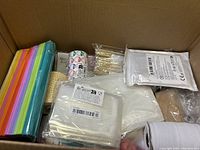 Photo of the box showing colorful tissue paper, rolls of stickers, twine, glue gun, and other stationery items.