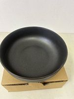 Top view of a black matte porcelain serving bowl on a cardboard box.