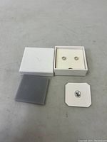Pair of Swarovski stud earrings in white box with lid, foam insert, and logo card.