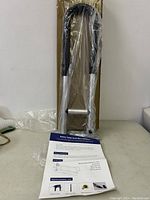 New safety toilet grab bar wrapped in plastic with mounting accessories and installation manual laid out on table.