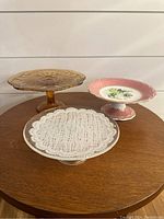 All three cake plates and dessert pedestals displayed on a wooden table.