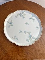 Top view of antique Theodore Haviland plate with blue floral patterns and gold trim on wood table.