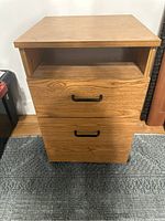 Front view of the file cabinet showing two drawers with black handles and an open shelf area on top.