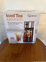 Box front showing 'Iced Tea Maker' branding by Capresso with product image and key features: 60 oz glass pitcher, adjustable brew strength, suitable for loose tea or tea bags, perforated water tank