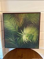 Front view of framed tropical leaf painting showing detailed green palm leaves.