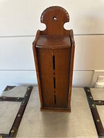 Front view of solid wood vintage match holder showing vertical slots and hinged lid.