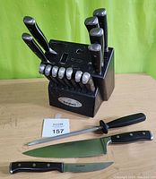 Side view of knife block with knives, sharpening steel and two kitchen knives laid out on table