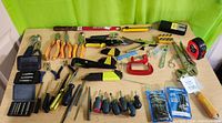 Full assortment of hand tools spread out on a table showing all contents including pliers, screwdrivers, clamps, wrenches, files, tape measure, and rulers.