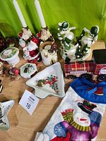 Close-up image of multiple Christmas decor pieces, including Santa standard candle holders, snowman candle holders, Santa Express train, a Christmas stocking holder, tree-shaped and star-shaped candy dishes, and other figurines.