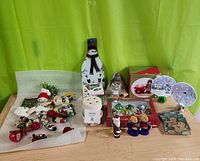 Full lot of assorted Christmas decorations on wood table with bright green background.