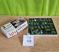 Photo showing boxed Singer Buttonholer kit alongside the multifunctional sewing foot kit showing all foot attachments in a plastic tray.