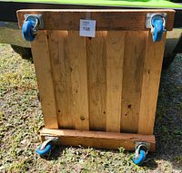 Bottom view of the wooden dolly showing the four blue 3.5-inch swivel casters attached to solid wood slats.