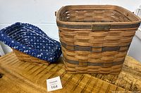 Photo showing both baskets together on a wooden surface: a rectangular Longaberger basket and a blue fabric-lined vegetable basket