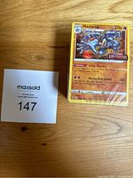 Shows the sealed stack of Pokémon cards with Machamp card visible on top and MaxSold lot card.
