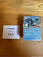 Front-facing view of the shrink-wrapped stack with the holographic Baxcalibur card visible on the front.