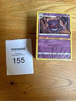 Front view of a stack of 50+ unopened Pokémon cards showing a Gengar Lost Origin card on top, shrink-wrapped tightly.