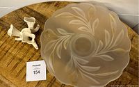 Top-down view of bowl showing frosted glass with leaf pattern and scalloped edges next to the white ceramic flower frog.