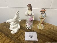 Three figurines side by side on wooden surface against a wall