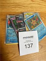 Front photo of a partial stack of Pokémon cards including Wartortle, Staryu, and several Japanese cards in protective sleeves on wood surface.