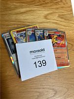 Pokémon cards fanned out on a wooden surface showing mix of characters and holographic designs.