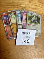 Front angled view of six Pokémon cards fanned out showing a mix of English and Japanese cards, including a Snorlax card and others, all sleeved in clear protective sleeves.