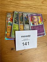 Front view of several Pokémon cards in sleeves showing a variety of holographic and standard cards including English and Japanese text