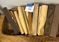 Top view of vintage wooden basket filled with multiple player piano rolls, some in cardboard boxes and some wrapped in kraft paper.