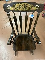 Full view of vintage wooden rocking chair showing floral painted design on top backrest and contoured seat with curved rockers.