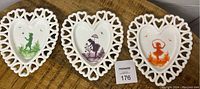 Set of three Westmoreland milk glass heart plates, showing each plate with different colored hand-painted designs and lattice edges.