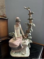 Front view of Lladro porcelain figurine showing seated lady, tree branch, base and birds