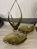 Photo showing the centerpiece and two matching bowls, olive green color with clear glass bases, placed on a white surface.