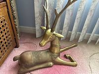 Full view of reclining brass deer figurine showing overall form, embossed body detail and patina.