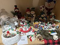 Full lot showing snowman figurines with detailed miniature winter village scenes inside, various small snowman ornaments, and Christmas themed decor.
