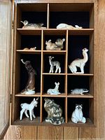 Wooden cubby shelf containing all 13 vintage porcelain animal figurines.
