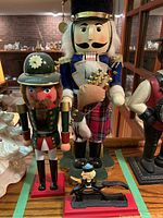 Two wooden nutcrackers and one small cast iron nutcracker on red base, showing detailed costumes and colors.