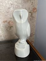 Front view of the white glazed ceramic owl sculpture showing facial features and posture on base.