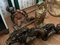 All three bronze-colored statues displayed together on floor.