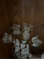 Display case with multiple Swarovski crystal figurines arranged on glass platforms