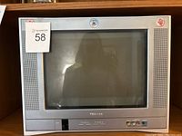 Front view of Toshiba CRT television showing the screen, speaker grilles on both sides, front control buttons, and AV inputs.