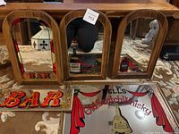Five vintage mirrored bar signs including wooden triple-panel mirror and two rectangular mirrored signs on carpeted floor.