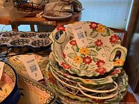 Four floral ceramic bakeware dishes stacked with wire racks underneath, showing off colorful flower pattern and handles.