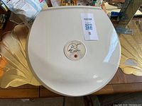 Top view of a white George Foreman Grill showing lid with a signature and circular power indicator.