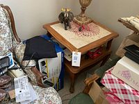 Photo of two-tiered end table with decorative inlaid tile top, wooden frame, lower shelf, and curved legs.