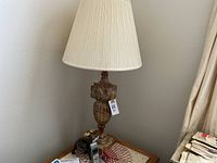 Photo of one marble lamp with beige pleated fabric shade on a wooden side table, showing intricate carved marble base and pleated lamp shade.