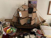 Image showing the wooden sailing ship model with cloth sails positioned on a stand among various household items.