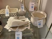 White porcelain bowl with scalloped edges, displayed alongside other porcelain items including a decorative swan dish and a white basket.