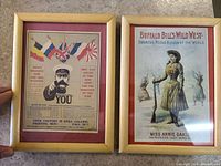 Framed World War One recruitment poster with Lord Kitchener pointing and enlistment details alongside framed Buffalo Bill's Wild West Annie Oakley poster.