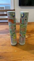Two cylindrical tubes decorated with jungle animal illustrations standing vertically on a wooden surface.